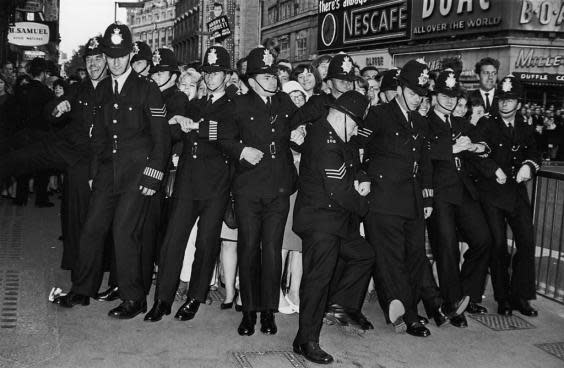 Policemen form a line to restrain female fans during the premiere of the new Beatles film ‘Help!’ at the London Pavilion, Piccadilly Circus, 29 July 1965 (Getty)