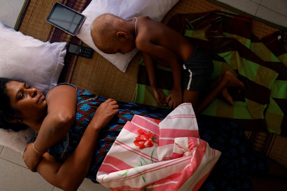 Ratnasingham Rajini watches her grandson S Saksan, 5, who has leukemia, while he sleeps in a corridor of a cancer care transit home (Reuters)