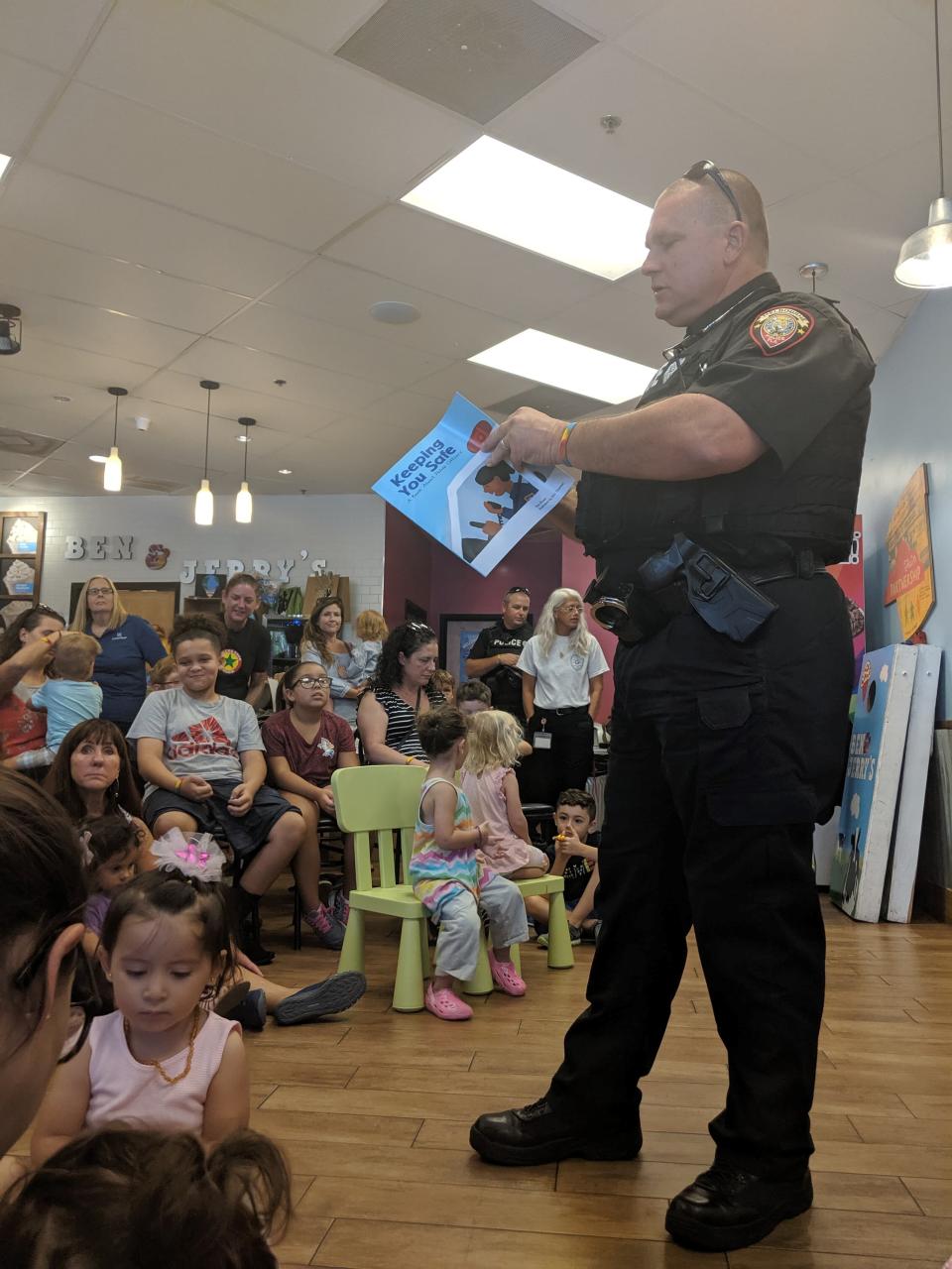 A Melbourne police officer reads children a story at an August 2019 Hey,Blue! event held at the Melbourne Ben & Jerry's.