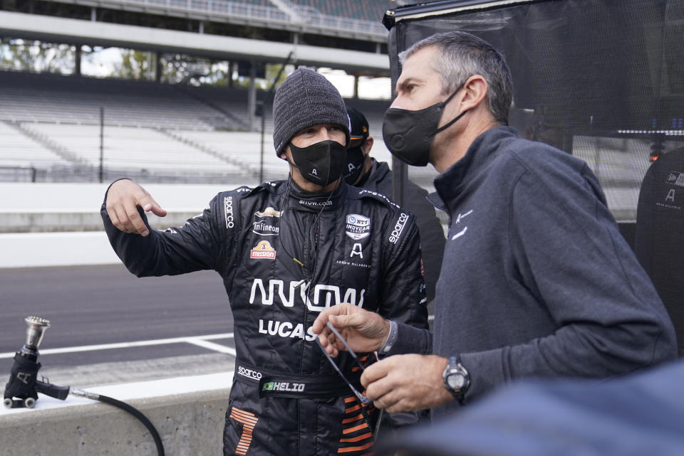 Helio Castroneves, left, of Brazil, talks with a crew member during a practice session for an IndyCar auto race at Indianapolis Motor Speedway, Thursday, Oct. 1, 2020, in Indianapolis. (AP Photo/Darron Cummings)