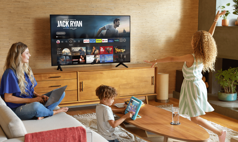 A family in the living room with a TV displaying an Amazon Fire TV homescreen.