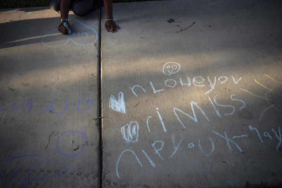 Chalk messages reading "I love you, I miss you," decorate the footpath at a memorial site in the town square, Friday, May 27, 2022, in Uvalde, Texas. In a town as small as Uvalde, even those who didn't lose their own child lost someone in the fatal school shooting. Some say now that closeness is both their blessing and their curse: they can lean on each other to grieve. But every single one of them is grieving. (AP Photo/Wong Maye-E)