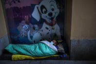 A homeless man wearing a mask sleeps in the doorway of a building, in Barcelona, Spain, Sunday, March 15, 2020. Spain's government announced Saturday that it is placing tight restrictions on movements and closing restaurants and other establishments in the nation of 46 million people as part of a two-week state of emergency to fight the sharp rise in coronavirus infections. For most people, the new coronavirus causes only mild or moderate symptoms. For some, it can cause more severe illness, especially in older adults and people with existing health problems. (AP Photo/Emilio Morenatti)