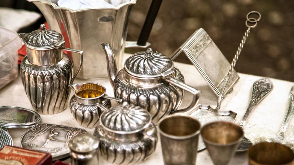 antique silver teapots, creamer and other utensils at a flea market