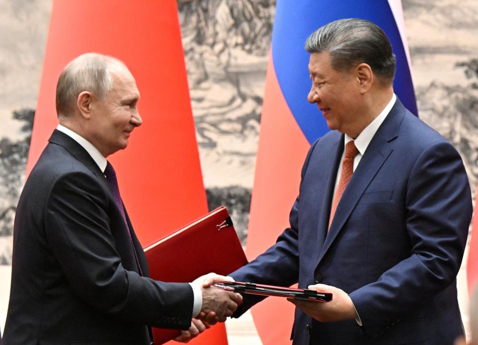 Russian President Vladimir Putin and Chinese President Xi Jinping exchange bilateral documents during a meeting in Beijing (via REUTERS)