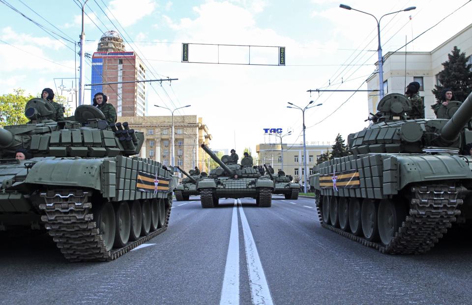 FILE - Tanks take part in the rehearsal of the military parade for the Victory Day to mark the 70th anniversary of the victory over Nazi Germany in World War II in Donetsk, rebel-held territory, Ukraine, May 5, 2015. A peace agreement for eastern Ukraine has remained stalled for years, but it has come into the spotlight again amid a Russian military buildup near Ukraine that has fueled invasion fears. On Thursday, Feb. 10, 2022 presidential advisers from Russia, Ukraine, France and Germany are set to meet in Berlin to discuss ways of implementing the deal that was signed in the Belarusian capital of Minsk in 2015. (AP Photo/Vasiliy Kolotilov, File)