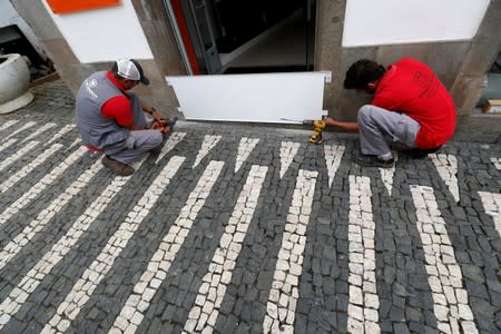 Two workers install a protection board before the arrival of Hurricane Lorenzo in Angra do Heroismo in the Azores islands