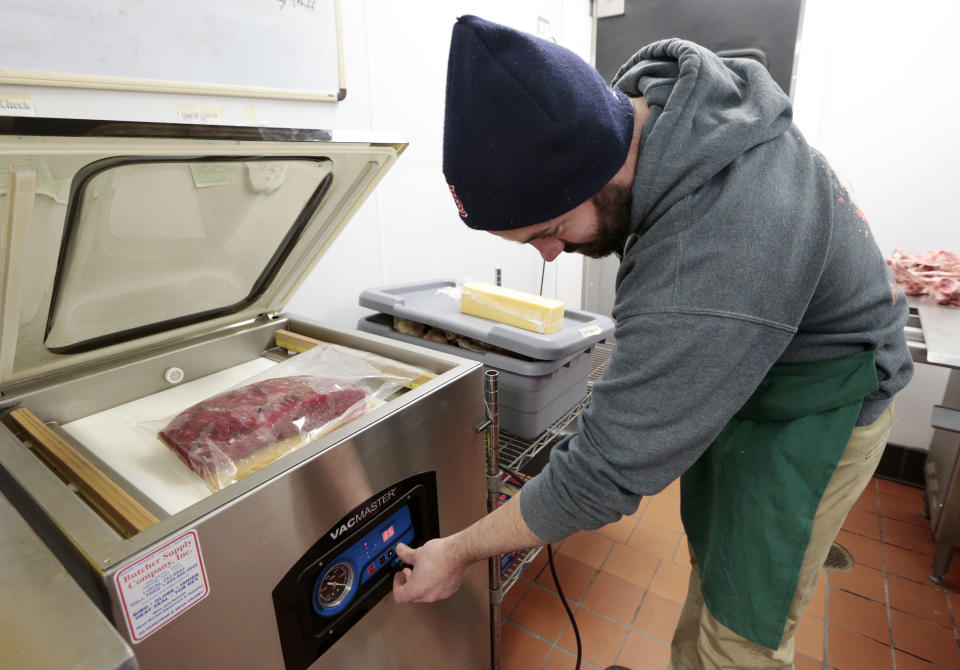 In this Dec. 11, 2013 photo, James Peisker vacuum-seals a bag containing a beef top round and a marinade as part of the process of preparing the "spiced round," a Christmastime beef specialty, at the Porter Road Butcher in Nashville, Tenn. The beef will marinate for six days. (AP Photo/Mark Humphrey)