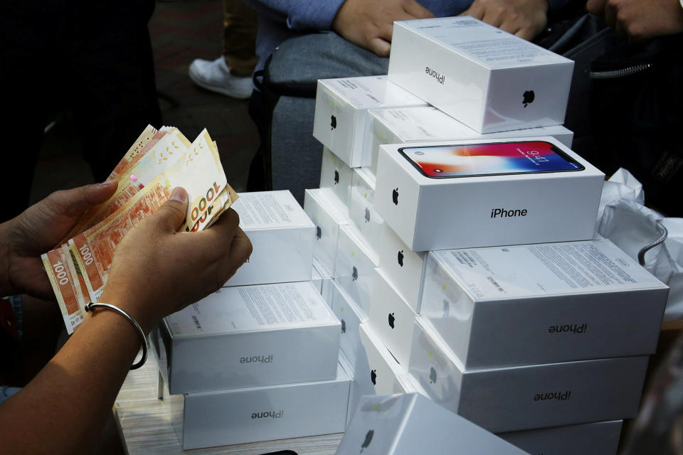 FILE PHOTO: A man pays to buy new iPhone Xs from those who just bought at Apple Stores, on a street in Hong Kong, China November 3, 2017. REUTERS/Bobby Yip