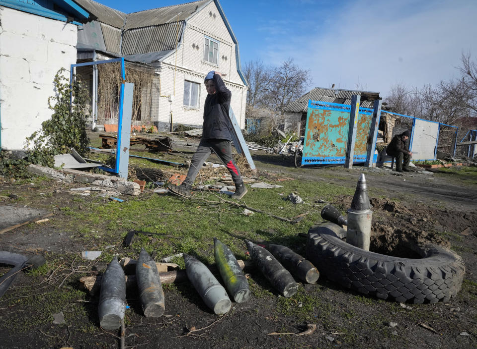 A boy walks by unexploded Russian shells in the village of Andriyivka close to Kyiv, Ukraine, Monday, April 11, 2022. Andriyivka was occupied by the Russian troops at the beginning of the Russia-Ukraine war and freed recently by the Ukrainian army. (AP Photo/Efrem Lukatsky)