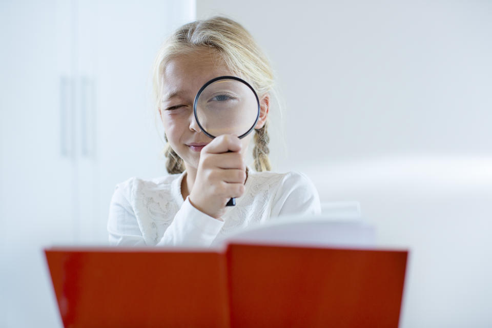 girl holding book and magnifying glass