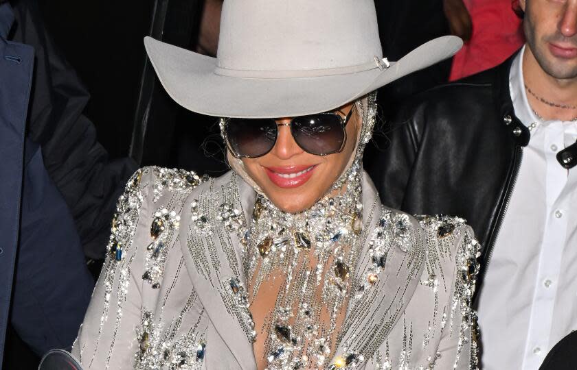 Beyonce wears a large white cowboy hat, sunglasses anda jeweled blazer to a fashion show