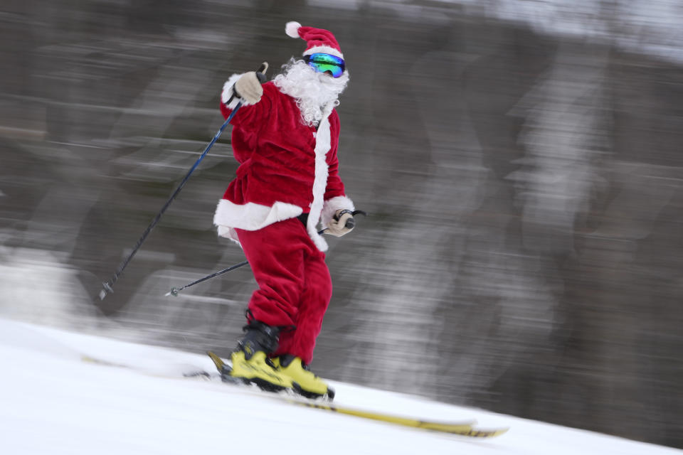 A skier dressed as Santa Claus gives a thumbs-up as they speed down the slopes.