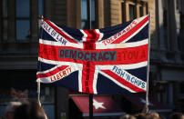 A British Union flag is held aloft bearing slogans including "Democracy", "Rule of Law", "Liberty", "Tolerance" and "Fish 'n' Chips", during the People's Vote March, in London, Saturday Oct. 20, 2018. Some thousands of protesters are marching through central London, Saturday, to demand a new referendum on Britain’s Brexit departure from the European Union. (Yui Mok/PA via AP)