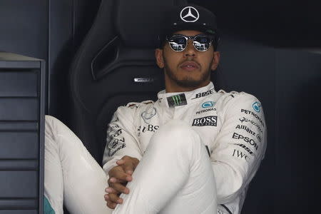 Mercedes Formula One driver Lewis Hamilton of Britain sits at his garage during the first practice session. REUTERS/Aly Song