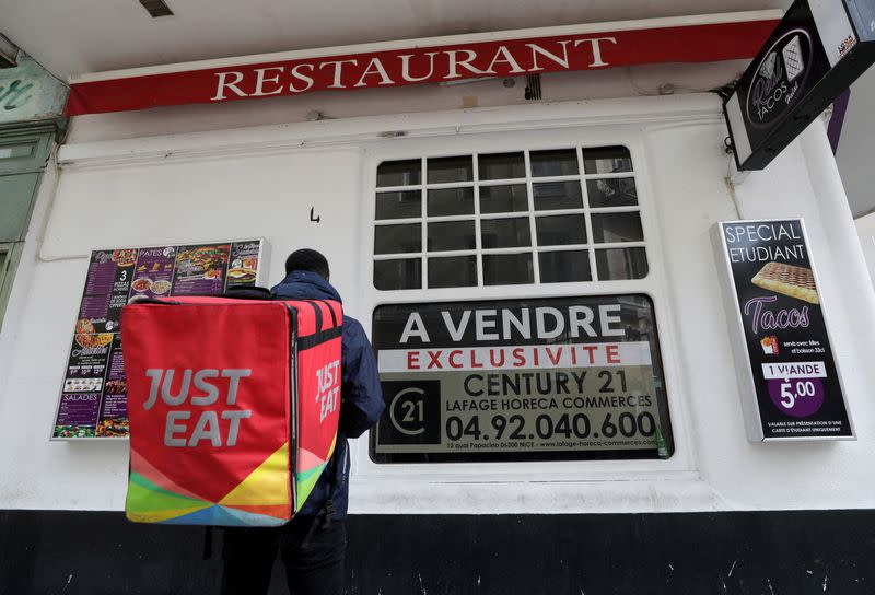 FILE PHOTO: A Just Eat delivery man stands in front of a closed restaurant on sale in Nice