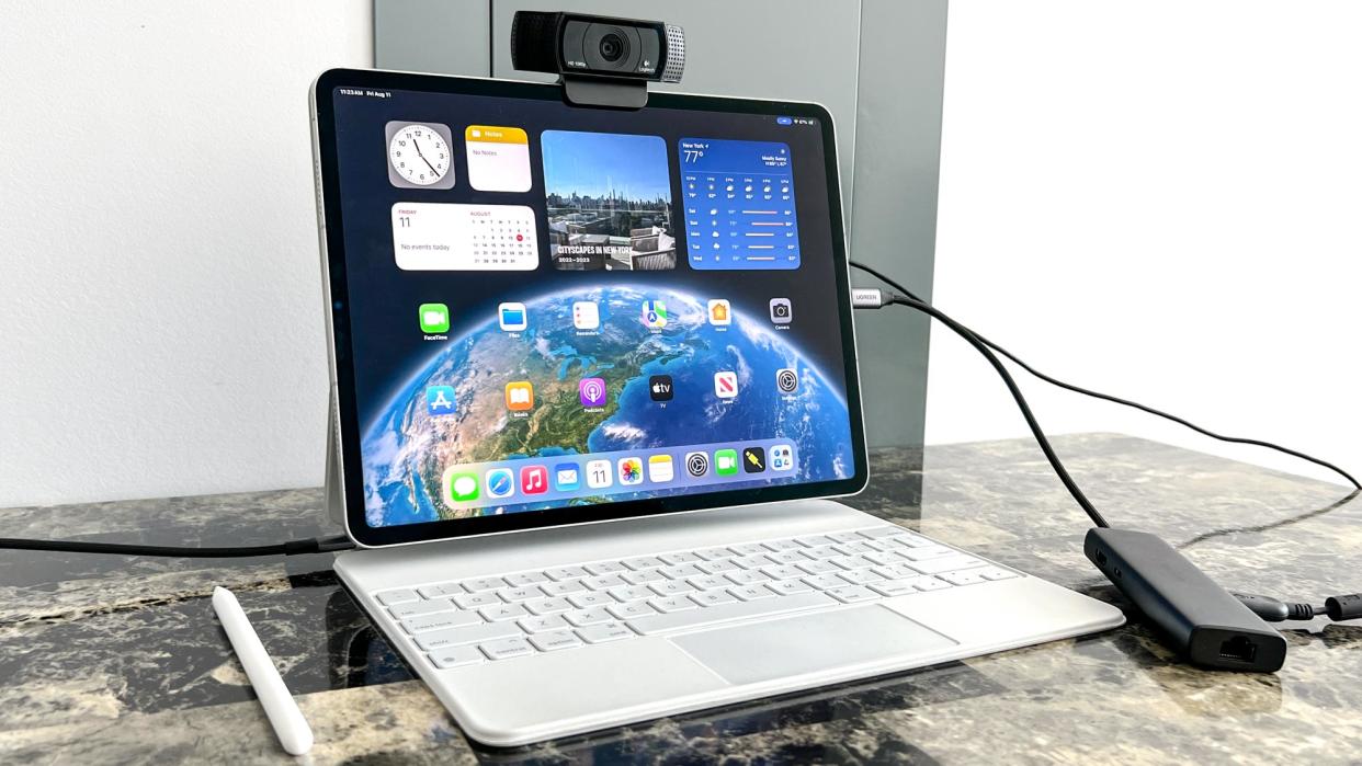  external USB webcam attached to the top of an iPad Air with Magic Keyboard showing home screen 