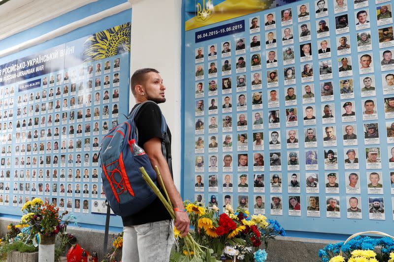 Ukrainian war veteran Viktor Pylypenko looks for a portrait of his comrade at the memorial wall for soldiers killed during the conflict in the country's east, in Kyiv