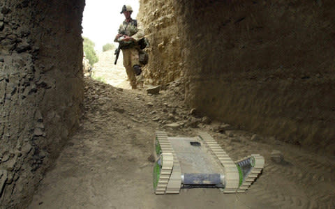 A U.S. Army soldier maneuvers Hermes the robot into a cave to detect mines, traps, and other unexploded ordnance  - Credit: AP