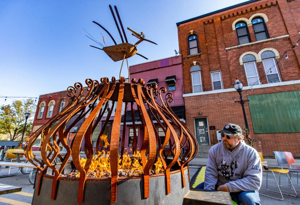 Bryan Williams lights the fireplace inside The Node, an outdoor dining and seating area located at the corner of North Second Street and East Main Street, in Niles on Friday. Williams, owner of the Brass Eye, says the people attracted to the gathering spot helped his business survive the pandemic.