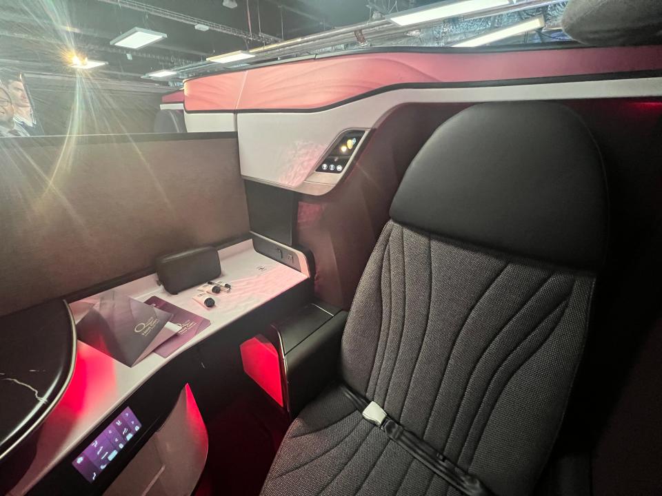 A QSuite Next Gen seat with a touchscreen and toiletries visible in the background at the 2024 Farnborough Airshow