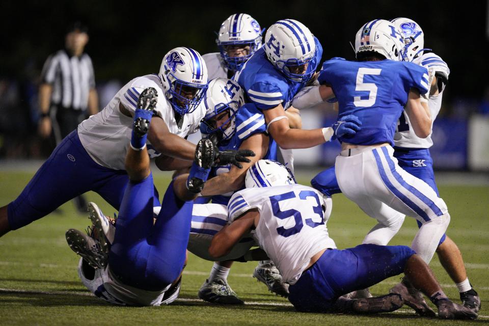 Highlands quarterback Brody Benke, center, is tackled by Simon Kenton's Desmond Betancourt (53) during a KHSAA high school football game at Highlands High School Friday, Aug. 26, 2022.