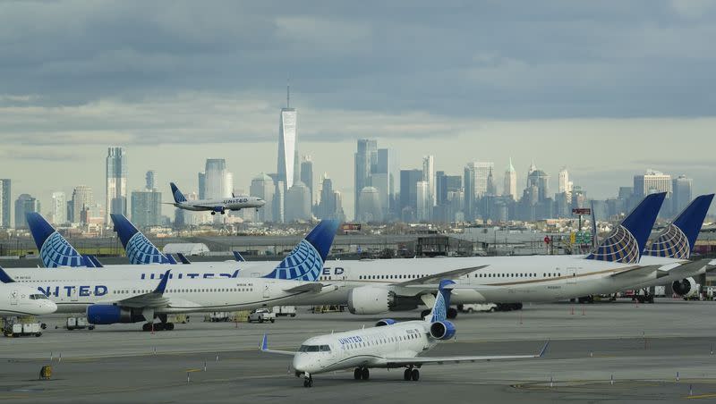 A United Airlines flight passes stationary United Airlines planes as it lands at Newark Liberty International Airport on Nov. 27, 2023, in Newark, N.J. The New York City skyline appears in the background.