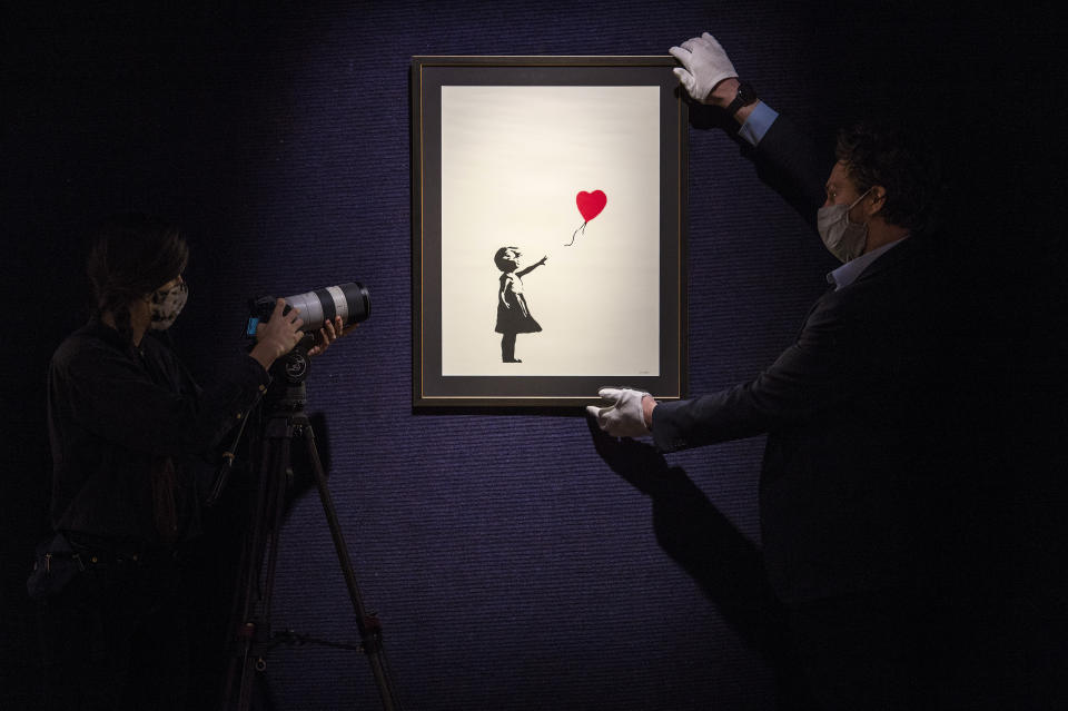 A gallery assistant is filmed looking at &#39;Girl With a Balloon&#39; by Banksy, on show at Bonhams London ahead of the forthcoming British. Cool. sale featuring works of art, photographs, designer fashion and entertainment memorabilia. Picture date: Monday February 22, 2021.