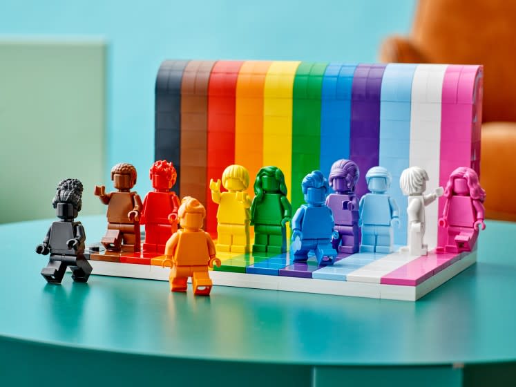 Various rainbow-colored Lego figurines displayed on a blue table