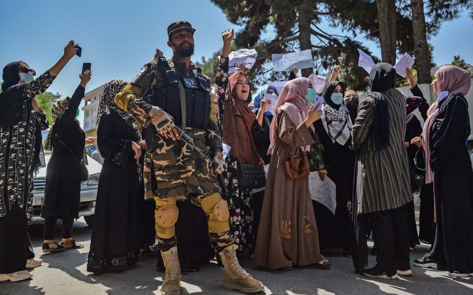 A Taliban fighter stands guard as Afghan women shout slogans during an anti-Pakistan protest rally, near the Pakistan embassy in Kabul - AFP 