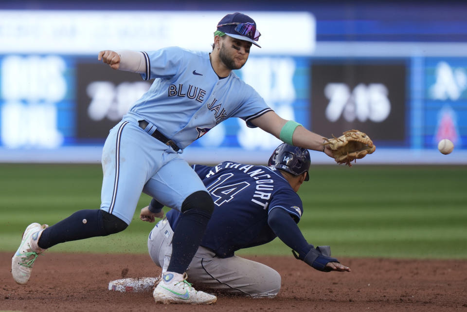 Tampa Bay Rays catcher Christian Bethancourt (14) is safe at third base after Toronto Blue Jays shortstop Bo Bichette (11) can't get to the throw during the sixth inning of a baseball game in Toronto, Saturday, Sept. 30, 2023. (Frank Gunn/The Canadian Press via AP)