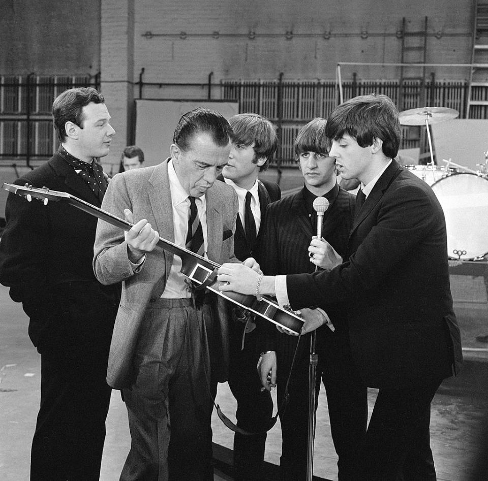 Ed Sullivan examines a guitar with The Beatles band members Paul McCartney, John Lennon, George Harrison, and Ringo Starr during a rehearsal