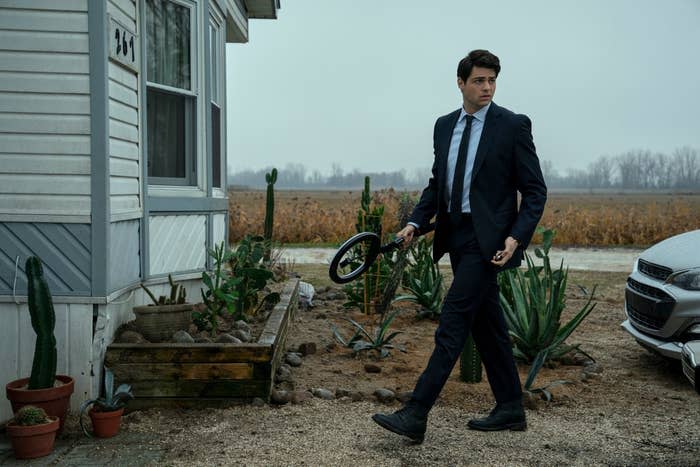 noah in a suit walking outside of a house