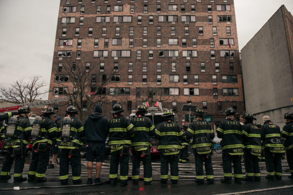 A line of firefighters standing outside the building that burned
