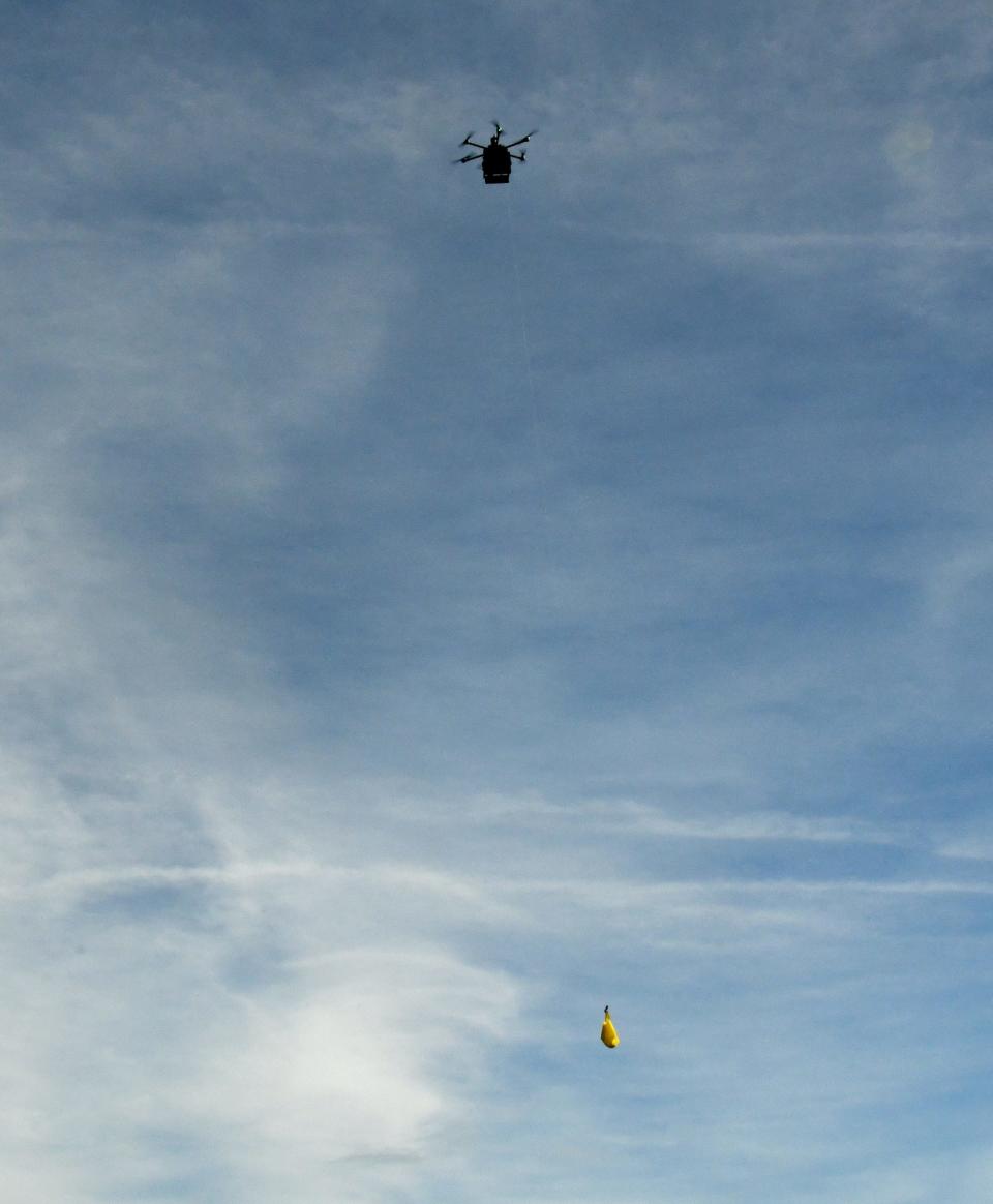 A Flytex autonomous drone lowers a yellow tote bag above the Florida Institute of Technology tennis courts during a Thursday demonstration flight.
