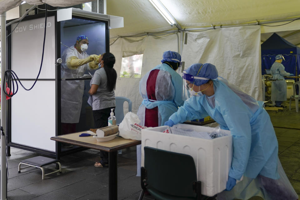 A doctor collects samples for a coronavirus test from behind a shield at a private hospital in Sunway, outside of Kuala Lumpur, Malaysia, on Wednesday, Oct. 7, 2020. The health ministry has warned that Malaysia is facing a new wave of virus cases as the outbreak has widened in recent days. New clusters have sprung up in many states amid increased travel to eastern Sabah state, a hotspot zone, for a state election last month. (AP Photo/Vincent Thian)