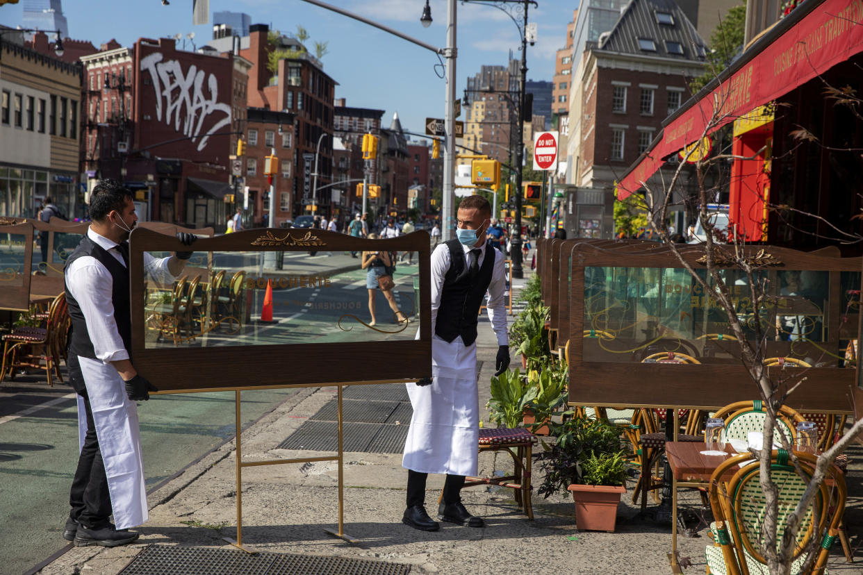 Waiters at a restaurant adjust social distancing screens outside for outdoor seating seating that follows current health guidelines to slow the spread of Coronavirus (COVID-19) at a restaurant in New York City, New York, U.S., June 25, 2020. REUTERS/Lucas Jackson     TPX IMAGES OF THE DAY