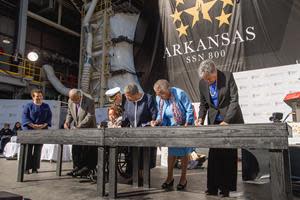 From left, NNS President Jennifer Boykin looks on as members of the Little Rock Nine, Ernest Green, Thelma Mothershed Wair assisted by PCU Arkansas commanding officer Cmdr. Adam Kahnke, Elizabeth Eckford, Gloria Ray Karlmark and Carlotta Walls Lanier, etch their initials onto steel plates during the keel authentication ceremony for Virginia¬-class submarine Arkansas (SSN 800) on Saturday, Nov. 19, 2022. (Photo by Ashley Cowan/HII)