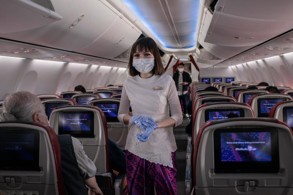 HONG KONG INTERNATIONAL AIRPORT, HONG KONG, CHINA - 2020/02/14: An airline staff member wears surgical mask inside an airplane at the Hong Kong International Airport. As the number of victims of the new Coronavirus increases, more countries cancel flights within and without the region. (Photo by Ivan Abreu/SOPA Images/LightRocket via Getty Images)