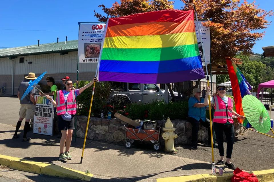 Frankie Leigh (right) and Skye Michelle hold a pride flag in front of protesters at Douglas County Pride in Roseburg, Oregon, in July 2023.