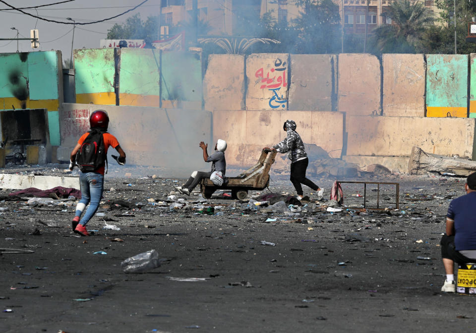 Riot police take cover behind a barricade during clashes with anti-government protesters, in Khilani Square, Baghdad, Iraq, Wednesday, Nov. 13, 2019. (AP Photo/Khalid Mohammed)