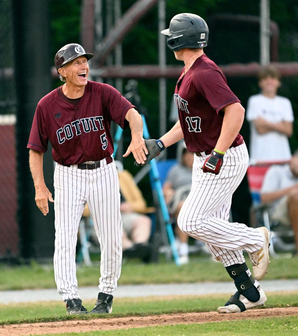 Sean Keyes of Cotuit is celebrated by his manager Mike Roberts as he rounds third on a home run against Falmouth in this Wednesday action.