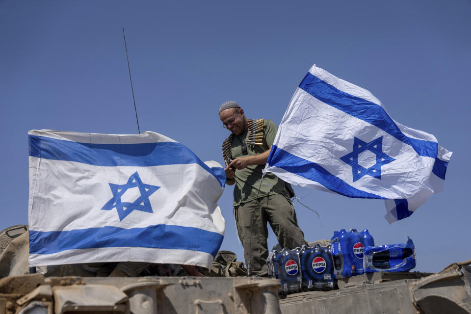 An Israeli soldier seen after he attaches an Israeli flag on top of an armoured personnel carrier (APC) near Israel's border with Gaza, in southern Israel, Thursday, June 6, 2024. (AP Photo/Ohad Zwigenberg)