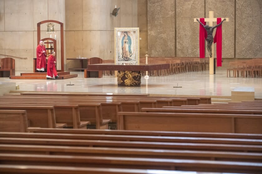 LOS ANGELES, CA - APRIL 10: Archbishop Jose Gomez, left, and Father Brian Nunez, right, celebrate Good Friday liturgy in a nearly empty Cathedral of Our Lady of the Angels, held on video streaming without parishioners to guard against the coronavirus on Friday, April 10, 2020 in Los Angeles, CA. (Brian van der Brug / Los Angeles Times)