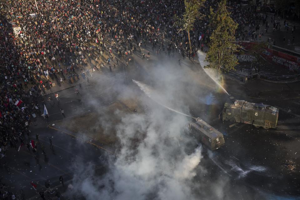 Demonstrators are sprayed by a police water cannon during an anti-government protest in Santiago, Chile, Friday, Nov. 1, 2019. Chile has been facing days of unrest, triggered by a relatively minor increase in subway fares. The protests have shaken a nation noted for economic stability over the past decades, which has seen steadily declining poverty despite persistent high rates of inequality. (AP Photo/Rodrigo Abd)