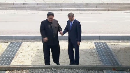 North Korean leader Kim Jong Un and South Korean President Moon Jae-in walk across the military demarcation line ahead of the inter-Korean summit at the truce village of Panmunjom, in this still frame taken from video, South Korea April 27, 2018. Host Broadcaster via REUTERS TV