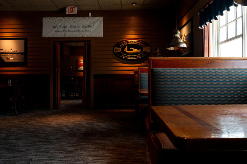 Interior of a Red Lobster restaurant with empty wooden booths and tables, dim lighting, and nautical-themed decorations on the walls