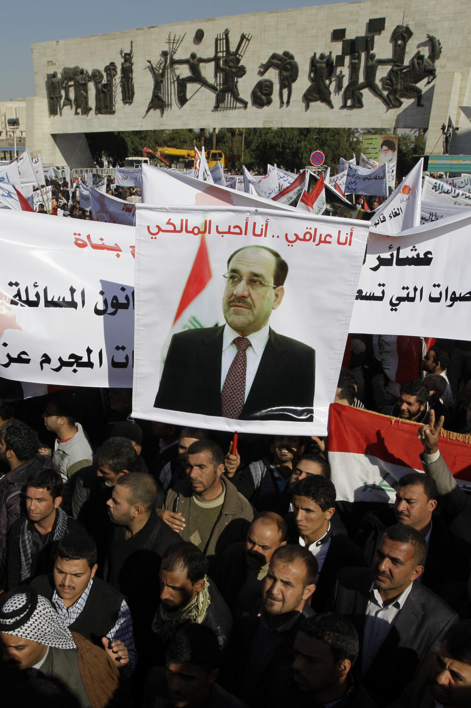 FILE - In this Jan. 12, 2013 file photo Shiite demonstrators chant pro-government slogans and wave national flags, to show support for Prime Minister Nouri al-Maliki, center in photo on banner, in Baghdad, Iraq. If Iraqi Prime Minister Nouri al-Maliki wins a third four-year term in parliamentary elections Wednesday, he is likely to rely on a narrow sectarian Shiite base, only fueling divisions as Iraq slides deeper into bloody Shiite-Sunni hatreds. (AP Photo/Khalid Mohammed, File)