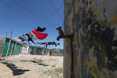 Clothing hangs above a communal tap in Khayelitsha township, near Cape Town, South Africa, December 12, 2017. The city has imposed severe restrictions in an attempt to avert "Day Zero", the point at which the dams run dry or have levels too low to use for potable water. Despite some winter rainfall dams are running dangerously low following the worst drought in a century in the region. REUTERS/Mike Hutchings