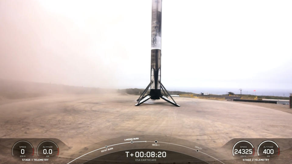 a white and black rocket rests on a concrete landing pad shortly after touching down